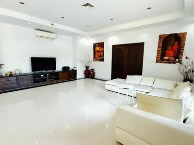 a living room with white furniture and a flat screen tv at Chuan SeaFront Villa Rawai Phuket in Rawai Beach