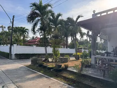a courtyard with palm trees and a white fence at Lantern Villa Private Pool Villa in Ban Klang