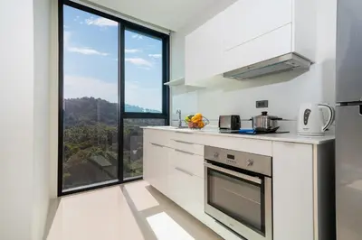 a kitchen with white appliances and a large window at Sea & Mountain Views Apartment A602 at VV Patong in Patong Beach