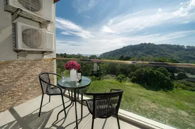 a table and chairs on a balcony with a view at Sea & Mountain Views Apartment A602 at VV Patong in Patong Beach