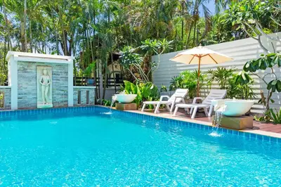 a swimming pool with chairs and an umbrella at 3BR Villa Barnabé with Lush Garden in Rawai Beach