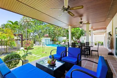 a porch with blue chairs and a ceiling fan at 3BR Villa Barnabé with Lush Garden in Rawai Beach