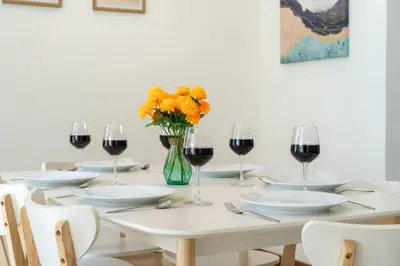 a table with glasses of wine and a vase of flowers at Goldena Twin Project - 3 Bedrooms Pool Villa in Kamala Beach