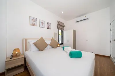 a large white bed in a room with a window at Goldena Twin Project - 3 Bedrooms Pool Villa in Kamala Beach