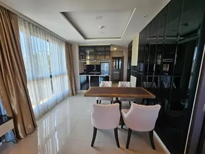 a dining room with a wooden table and white chairs at 2-Bedrooms Seaview Suite in Surin Beach in Surin Beach