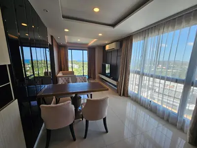 a dining room with a table and chairs and windows at 2-Bedrooms Seaview Suite in Surin Beach in Surin Beach