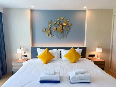 a bedroom with a large white bed with yellow pillows at Duplex Cala 1BR FamilyPoolsGym Shuttle in Rawai Beach