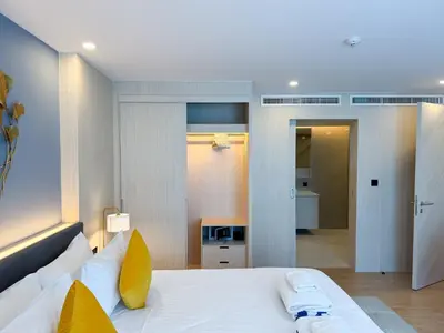 a bedroom with a large white bed with yellow pillows at Duplex Cala 1BR FamilyPoolsGym Shuttle in Rawai Beach