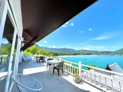 a balcony with a table and chairs and a view of the water at Jaokhun Bayview Kamala, Phuket in Kamala Beach