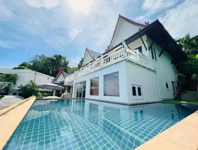 a villa with a swimming pool in front of a house at Jaokhun Bayview Kamala, Phuket in Kamala Beach