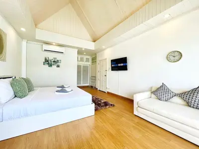 a living room with a couch and a clock on the wall at Jaokhun Bayview Kamala, Phuket in Kamala Beach