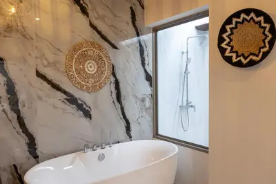 a bathroom with a white tub and a marble wall at 3 Bedrooms Private Pool Villa near Laguna in Laguna Phuket
