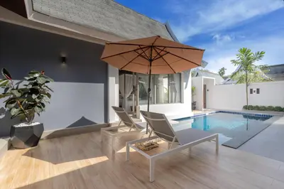 a patio with chairs and an umbrella and a pool at 3 Bedrooms Private Pool Villa near Laguna in Laguna Phuket