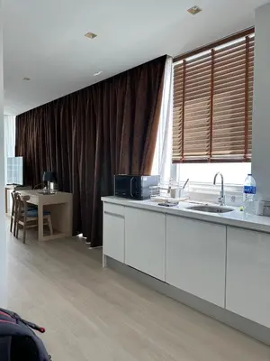 a kitchen with white cabinets and a table and a window at The beach front Condo in Ban Saiyuan (1)