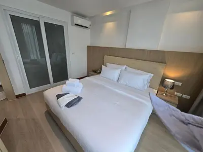 a bedroom with a large white bed with towels on it at The beach front Condo in Ban Saiyuan (1)