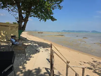 a person sitting on a bench on the beach at The beach front Condo in Ban Saiyuan (1)