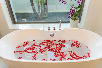 a white bathroom sink with red flowers in it at Lumière Villas Phuket - Golfside Retreat in Laguna in Laguna Phuket