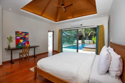 a bedroom with a bed and a desk and a window at Luxury 5 Bedroom Staffed Botanica Villas in Ban Phru Champa