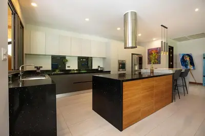 a large kitchen with a black island in the middle at Luxury 5 Bedroom Staffed Botanica Villas in Ban Phru Champa