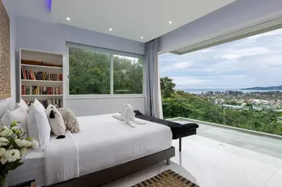 a bedroom with a white bed and a large window at Seaview three bedroom villa in Bangtao area in Ban Thalat Choeng Thale