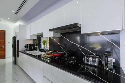 a kitchen with white cabinets and a black counter top at Seaview three bedroom villa in Bangtao area in Ban Thalat Choeng Thale