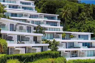 a large white apartment building with trees in the background at The View Phuket F9 in Kata Beach