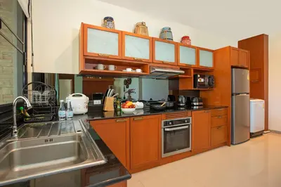 a kitchen with wooden cabinets and stainless steel appliances at Tropical 2BR Pool Villa 3D12 in Gated Residence Rawai VIP Villas in Rawai Beach
