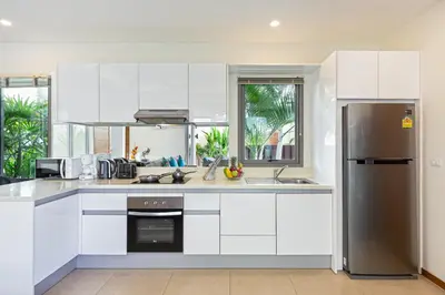 a kitchen with white cabinets and a stainless steel refrigerator at Modern Thai-Balinese 2-Storey Pool Villa Kael in Ka Villas Residence, 500m from Famous Rawai Beach Seafood Market in Rawai Beach