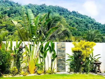 a garden with palm trees and a white fence at 20 - Tranquil Retreat near Marriott Naiyang Beach in Nai Yang Beach