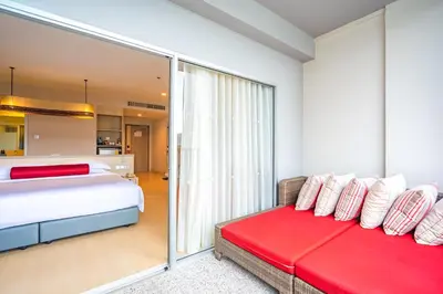 a bedroom with a bed and a red couch at Ramada by Wyndham Phuket Deevana in Patong Beach