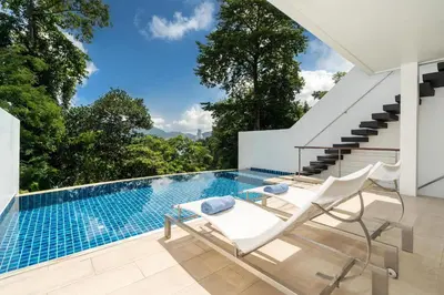 a swimming pool with two chairs and a table at Atika Villa 7 ocean view pool villa in Patong Beach