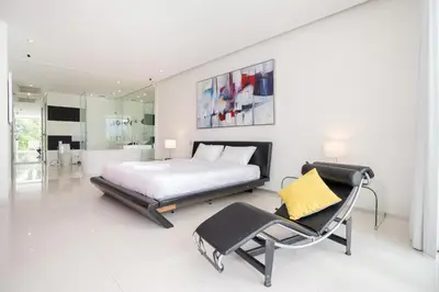 a white bedroom with a bed and a chair at Atika Villa 7 ocean view pool villa in Patong Beach