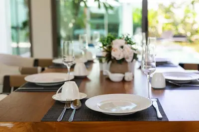 a wooden table with white plates and glasses on it at Luxury Villa in heart of Bang Tao! Villa BEAM in Laguna Phuket