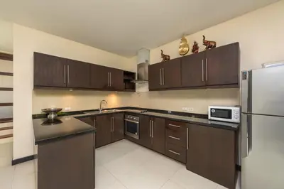 a kitchen with wooden cabinets and a refrigerator at Villa Iorangi 3 Bedroom Private Pool in Rawai Beach