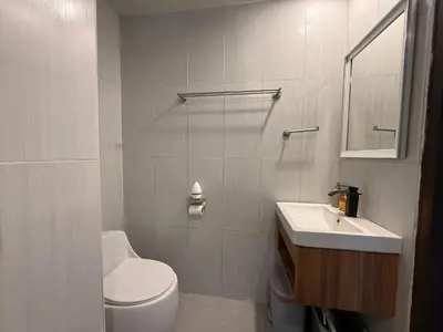 a white bathroom with a toilet and a sink at Newly Renovated Sea View House in Karon Beach