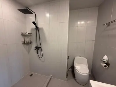 a white bathroom with a toilet and a shower at Newly Renovated Sea View House in Karon Beach