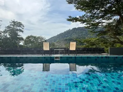 a swimming pool with two chairs and a table at Ananda Place in Ban Pa Khlok