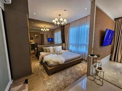 a bedroom with a large bed and a living room at The City Condo Near Central Fest Phuket, Pool view in Ban Sam Kong