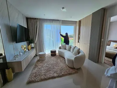 a woman standing in a living room looking out the window at The City Condo Near Central Fest Phuket, Pool view in Ban Sam Kong