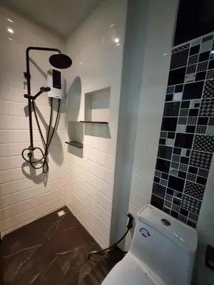 a bathroom with a toilet and a tile wall at Nua Tone Riverside Resort in Ban Thalat Choeng Thale