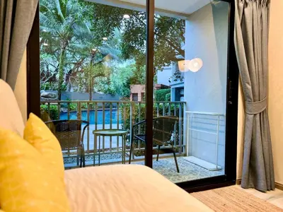 a room with a bed and a view of a balcony at The Title NaiyangPhuket1 in Phuket
