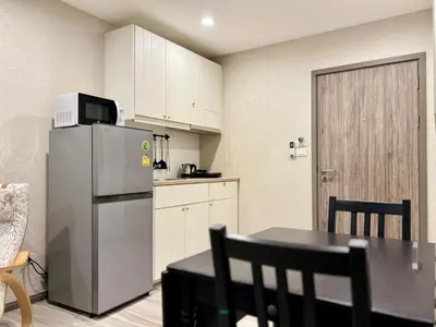 a kitchen with a refrigerator and a table with chairs at The Title NaiyangPhuket1 in Phuket