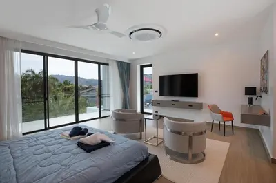 a bedroom with a large bed with a television and chairs at villa Lahaina in Rawai Beach