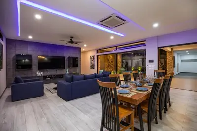 a dining room and living room with a table and chairs at Stunning 4 bedrooms pool villa at Rawai kokmakham 2 in Rawai Beach