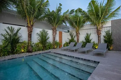 a swimming pool with chairs and palm trees at Stunning 4 bedrooms pool villa at Rawai kokmakham 2 in Rawai Beach