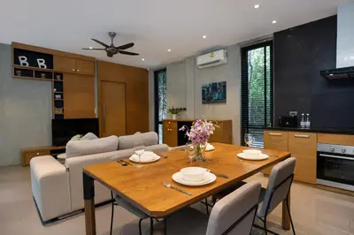 a dining room and living room with a wooden table at 1BR Pavilion Natural Park P07 Kamala Beach in Kamala Beach