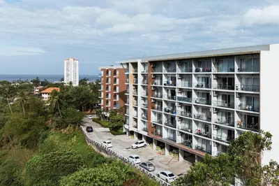 an apartment building with cars parked in front of it at Karon Beach Hill View Appartment in Karon Beach