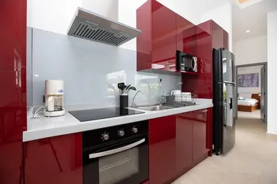 a kitchen with red cabinets and a black refrigerator at Villa Malaki, pool villa 2 bedrooms at rawai in Rawai Beach