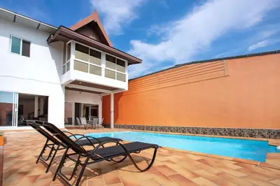a patio with two chairs next to a swimming pool at Family Holiday 3BR Pool Villa Lancelot 2 in Rawai Beach
