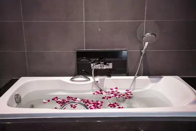 a bath tub with a faucet with flowers in it at Private 4BR Pool Villa Skylight with Stunning Views of Kamala Green Hills in Kamala Beach